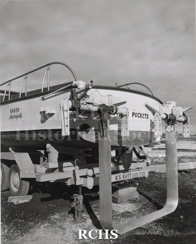 Black and white photograph of "High Pockets" on a trailer at Russell Marina, Westport, WI. The words "High Pockets" are painted on the back.