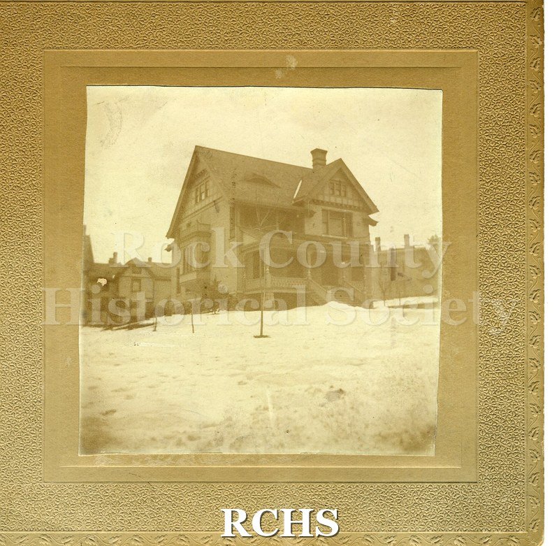 Black and white photograph of Dr. James Mills' Residence, a three story house with a porch along the front of it. There is snow up to the porch steps.
