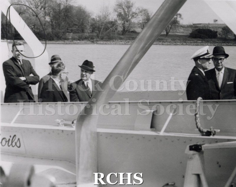 Black and white photograph of a hydrofoil in water. Shows a portion of a boat with six people in it. On a separate card: "Chief Petty Officer-Sheehan J. G.