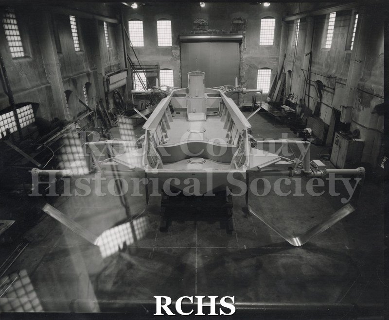 Black and white photograph of a hydrofoil boat in a building.