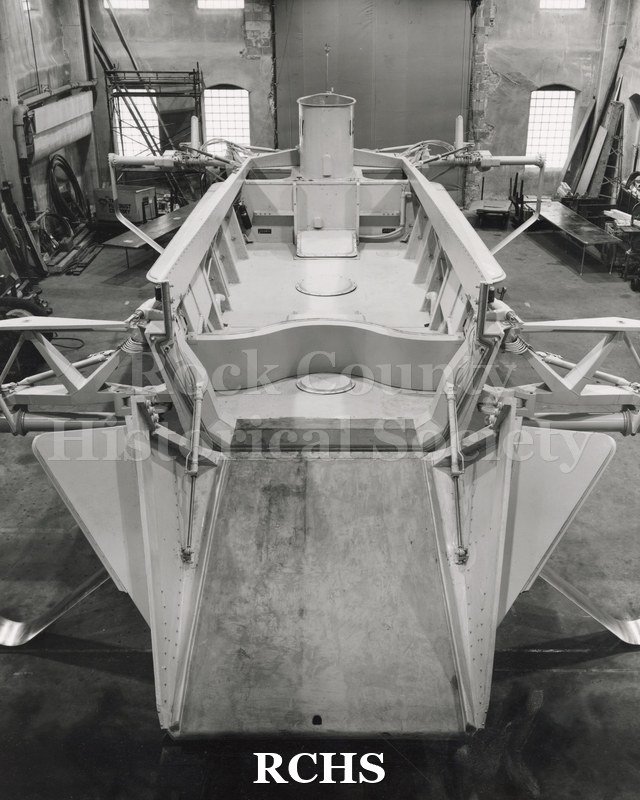 Black and white photograph of a hydrofoil boat in a building. Landing panel is down.