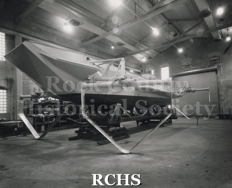 Black and white photograph of LCVP. Shows foils of the boat on the ground in a building.