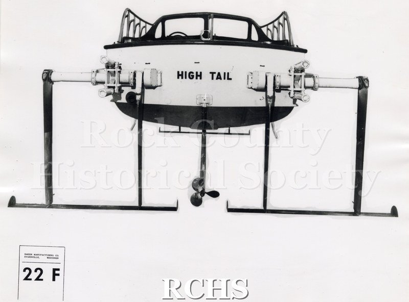 Black and white photograph of "High Tail" front view with a propeller on the bottom. The name "High Tail" is on the stern. On bottom: "Baker Manufacturing Co.