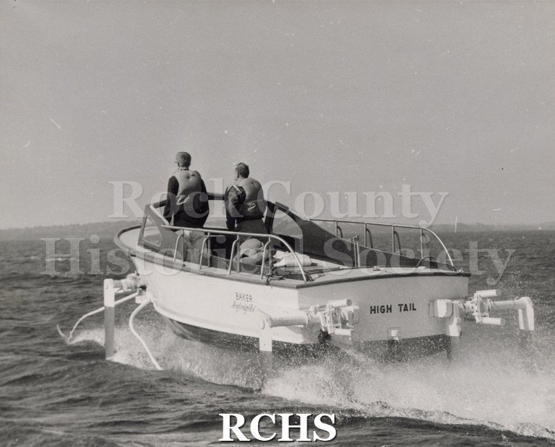 Black and white photograph of "High Tail" in the water with two men aboard. Boat is going away from camera. On separate card: "High Tail" David Quick Neil Lien".