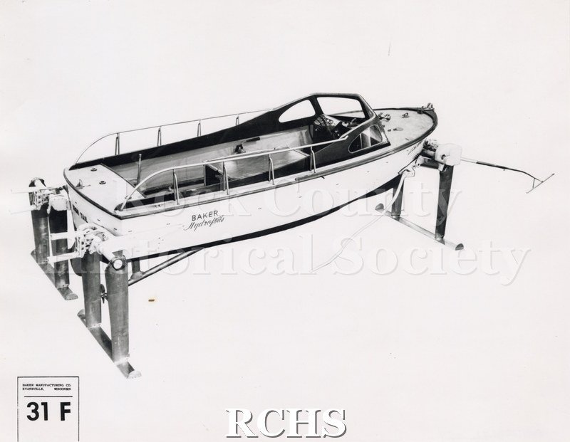 Black and white photograph of "High Tail" hydrofoil with a back/side view. The name: "Baker Hydrofoils" is visible on the side. On bottom: Baker Manufacturing Co.