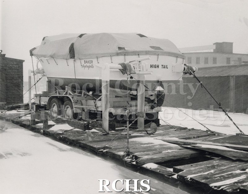 Black and white photograph of "High Tail" on a trailer. There is a tarp on the top of the boat.