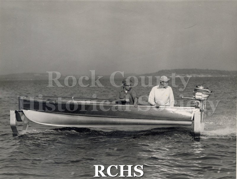 Black and white photograph of the first hydrofoil outboard with two men on board. On separate card: "1st hydrofoil outboard Wallace Olsen Jerome Matson-statistician".