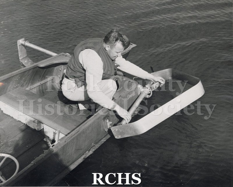 Black and white photograph of the front end of an outboard hydrofoil. Man in front is lowering the foil into the water. On separate card: "Max Palmer outboard HF".