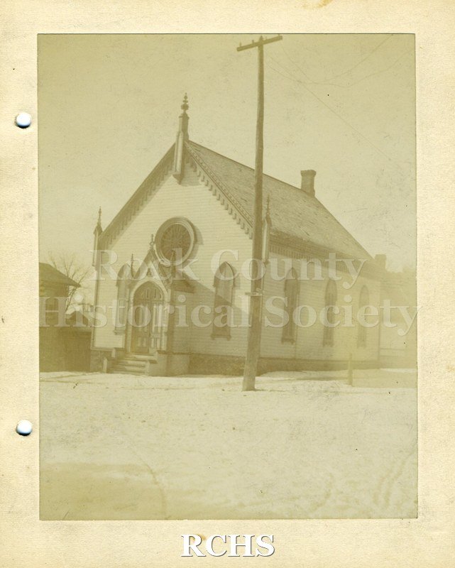 Black and white photograph of Scandinavian Lutheran Church. Shows a small wooden church with a round window above the door.