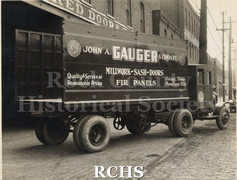 Black and white photograph of a trailer from Highway Trailer Co., Edgerton, WI. Shows a truck with a trailer on back. The sign reads: " John A. Gauger & Company.