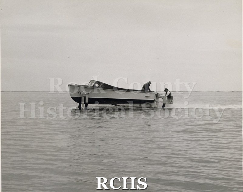 Black and white photograph of a Naval Boat in water with two men aboard.
