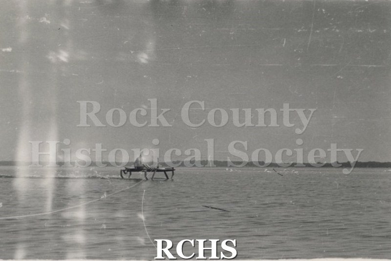Black and white photograph of a hydrofoil in the water with a man sitting in it. Description given: "Foil testing-J. G.