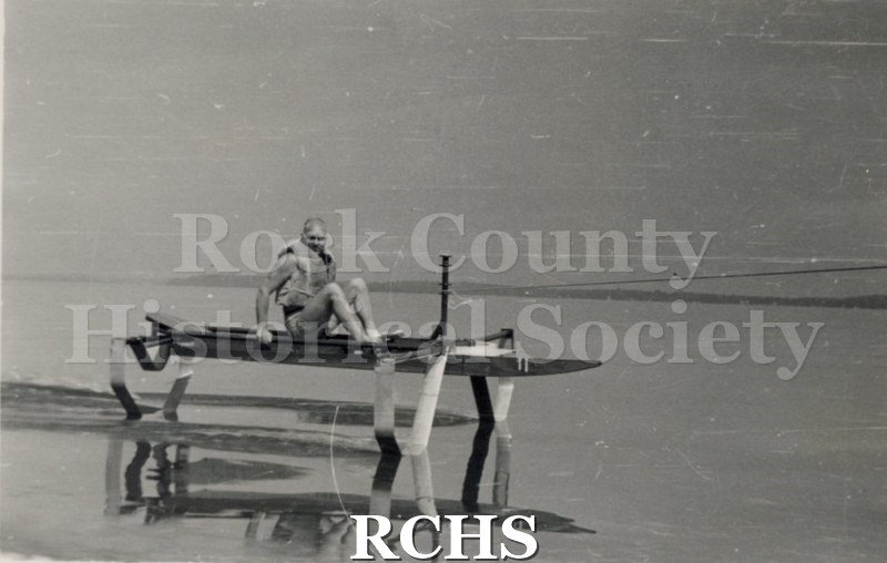 Black and white photograph of J. G. Baker sitting in a hydrofoil that is stationary. Description given: "Foil testing-J. G.