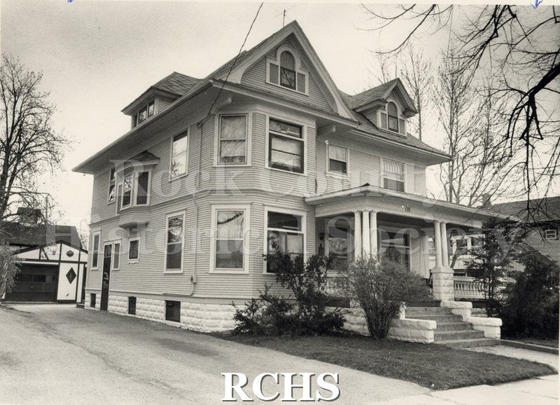 Black and white photograph of 115 S. High St., Janesville, WI. Shows a three story house with a porch. Garage is visible behind the house. On bottom: "Eldridge".