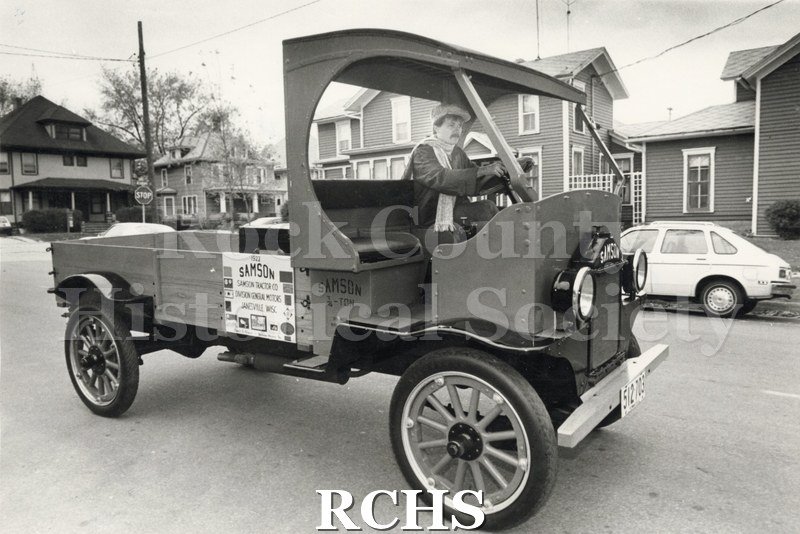 Black and white photograph of Dudley Kimball driving a Samson Truck. There is a sign: "1922 Samson Samson Tractor Co.