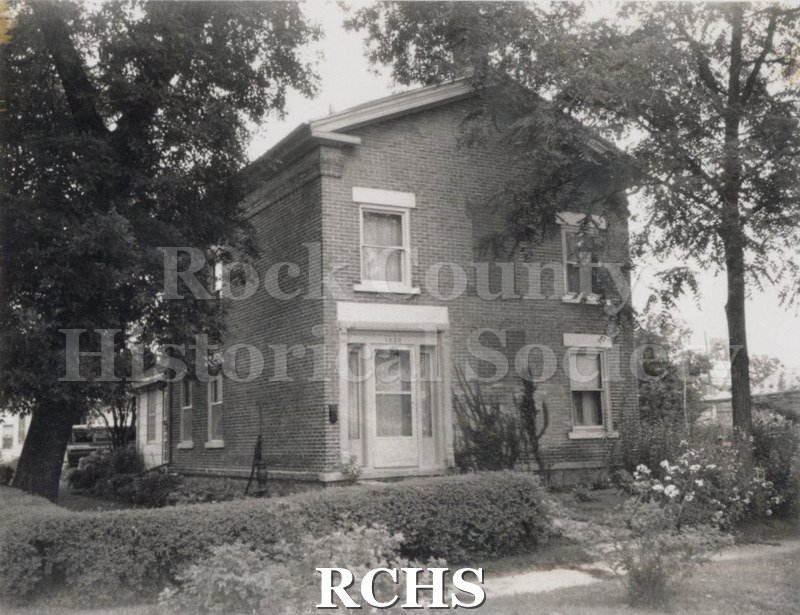 Black and white photograph of the Risches residence, a two story brick house with the entrance on the left.