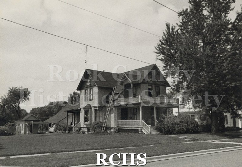 Black and white photograph of the Arnold-Stone Residence, a two story house with a porch on the front and a balcony above it.