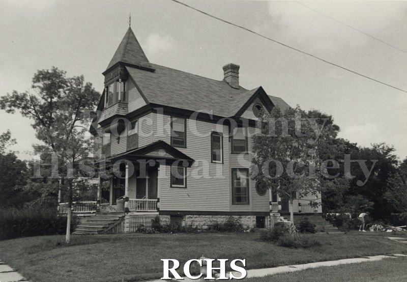 Black and white photograph of the Jackie & Bill Wood residence, a three story house with a peaked structure on the roof.