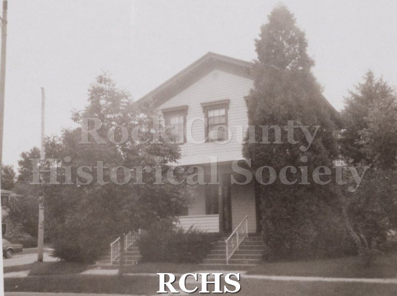 Black and white photograph of the ome at 176 S.Franklin St., a two story house with a porch.There is an evergreen tree on the right and other trees around the house.