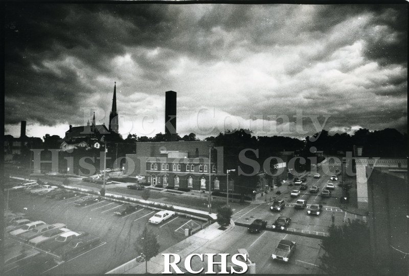 Black and white photograph of St. Mary's church on the far left with other buildings and cars to the right.
