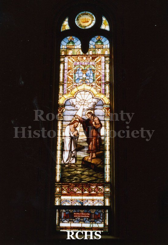 Color photo of a stained glass window in St. Patrick's Catholic Church, Janesville, WI, with John the Baptist baptising Jesus.