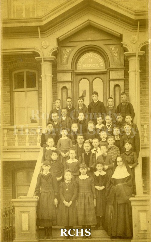 Sepia photo of school children and a nun on the steps of St. Joseph's Convent of Mercy.