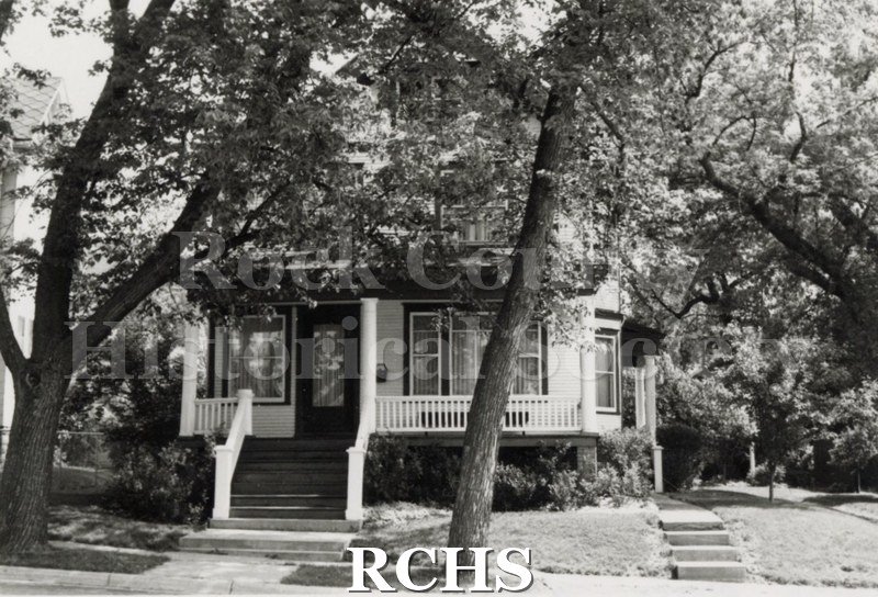 Black and white photograph of Cindy Simpson's home on Wisconsin Street, a three story house with a large porch across the front.