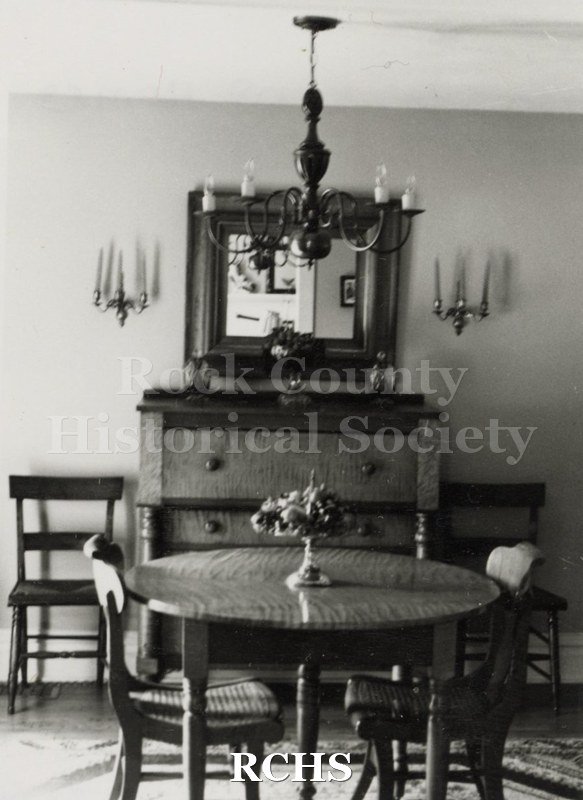 Black and white photograph of the dining room in the Wolfgram home with a round table and four chairs.