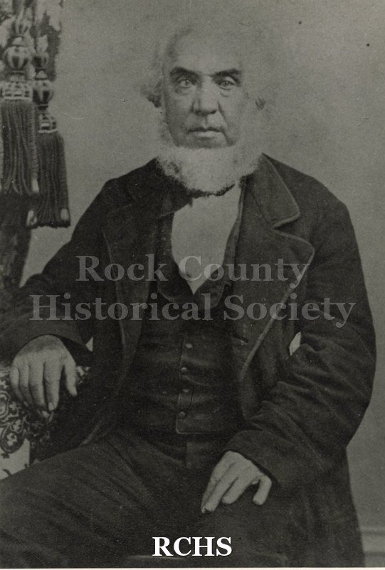 Black and white photograph of Henry Fletcher Janes with a white beard sitting in a chair. He is dressed in a dark suit with a vest and white shirt.