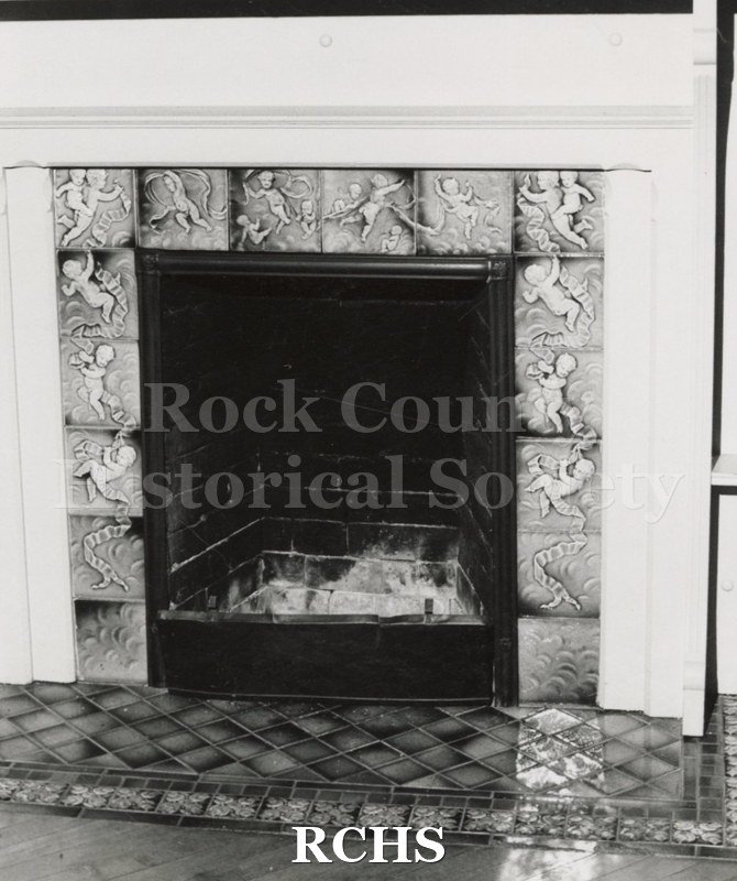 Black and white photograph of the Pliny Norcross-David Holmes residence. Shows a fireplace with a decorative frieze on top and on each side of the fireplace.