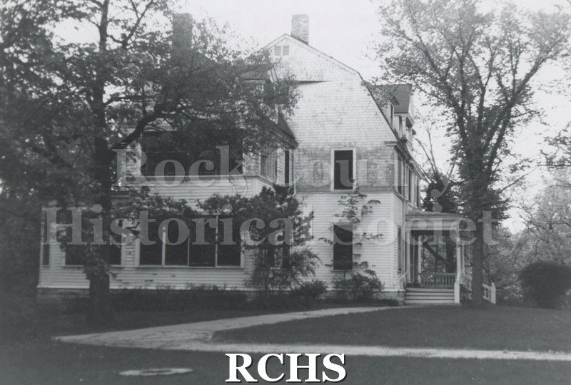 Black and white photograph of the Pliny Norcross-David Holmes residence. Shows a three story house shown from the side. It has a porch extending on the right.