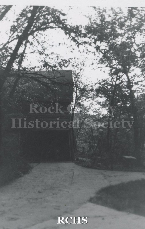 Black and white photograph of the Pliny Norcross-David Holmes residence. Shows a three story house barely visible through the trees.