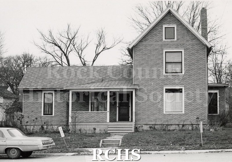 Black and white photograph of 1017 Olive St., Janesville, WI, demolished c. July 1, 1971. Shows a house with one story on the left and three stories on the right.
