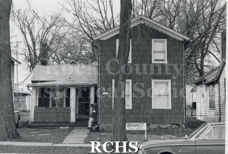 Black and white photograph of 537 N. River St., Janesville, WI, demolished c. July 1, 1971. Shows a house with two stories on the right and one story on the left.