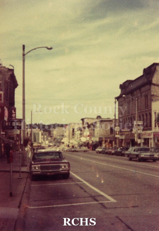 Color photo looking down W. Milwaukee Street showing stores along both sides of the road.