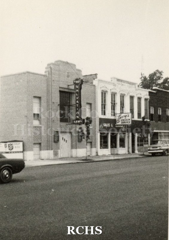 Black and white photograph of stores on N. Main Street, Janesville, WI, On the left is the Salvation Army and on the right is Larry's Vacuum.