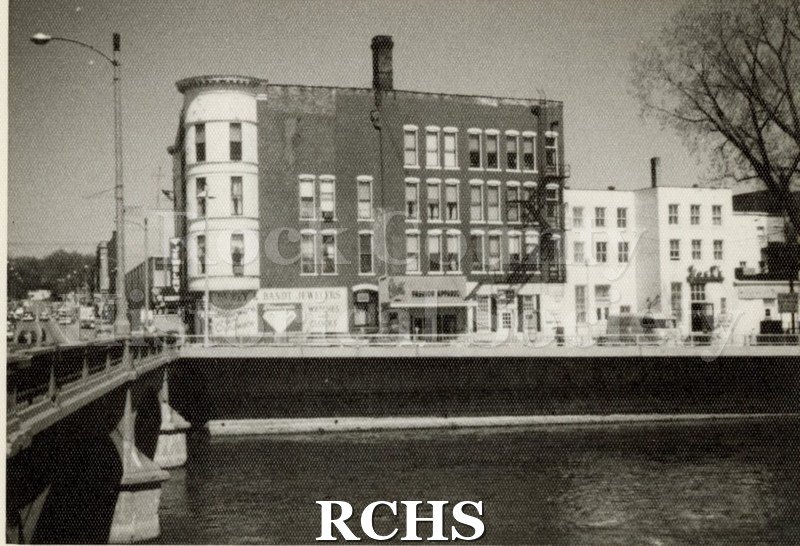 Black and white photograph of the back of the Hayes Block taken from across the river.