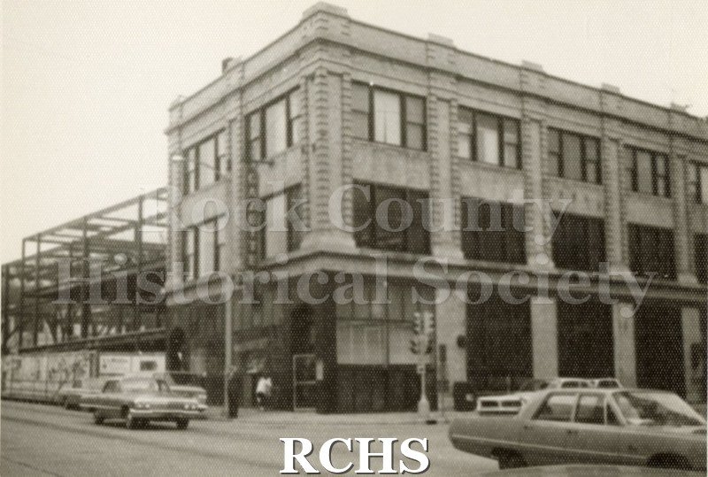 Black and white photograph of the Janesville Gazette Building. Shows a three story building with a sign for "Gazette" on it.