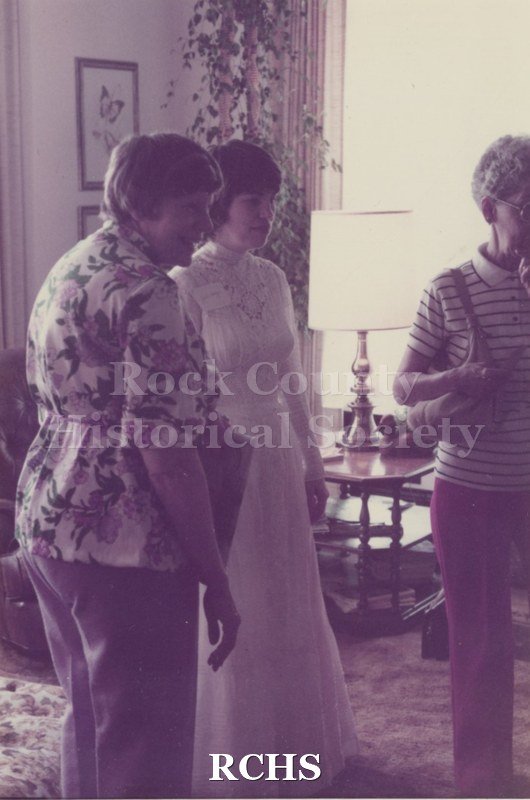 Historic image of Tinted photographof an unidentified house on 1984 Janesville Historic House Tour. Shows three people standing in the living room of a house.