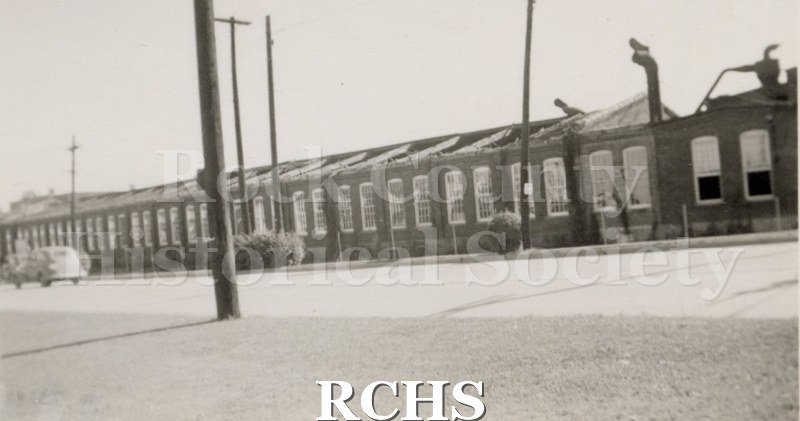 Black and white photograph of the Hough Shade plant, S. Jackson St. Shows tornado damage Aug. 20, 1938. This is a long building with many windows.