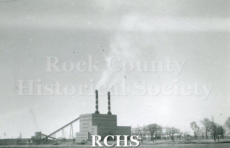 Black and white photograph of Rock River Generating Plant WPL, an electrical generating plant, shown from a distance.