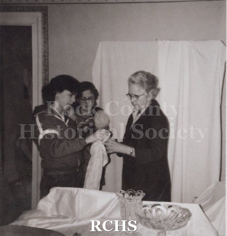 Black and white photograph of Emily Debroux, Mary Nelson, and Ruth N. Hughes in the Tallman House with glassware on the table.