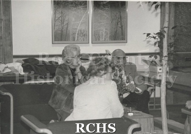 Black and white photograph of Art Levzow and two women listening to someone.