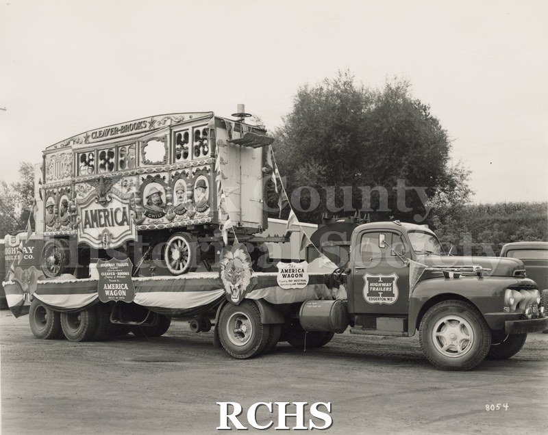 Black and white photograph of a circus wagon on a flat bed truck.