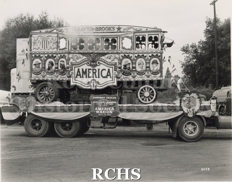Black and white photograph of a circus wagon on a flat bed truck.