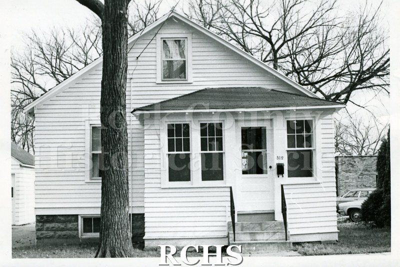 Black and white photograph of 512 Madison St., Janesville, WI. Shows a small two story house with an enclosed porch. The number "512" is visible above the mailbox.