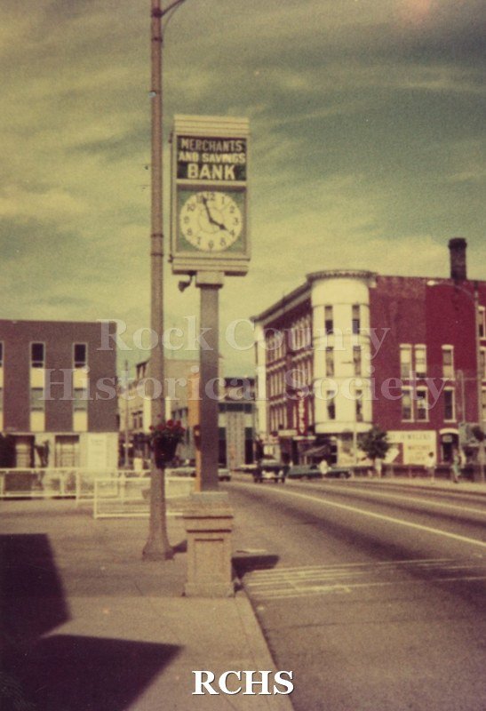 Color photo of the Hayes block and Merchants and Savings Bank buildings. Shows the clock in front of the bank.