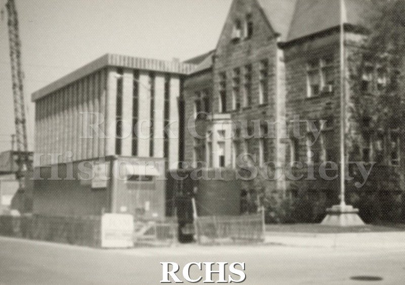 Black and white photograph of Janesville City Hall. Construction is going on as there is a crane on the far left.