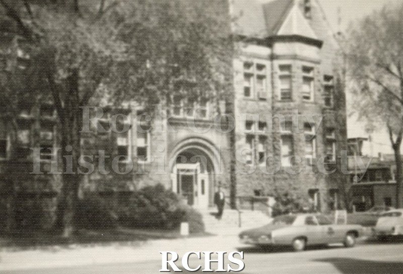 Black and white photograph of Janesville's City Hall. There is a man coming out of the building.