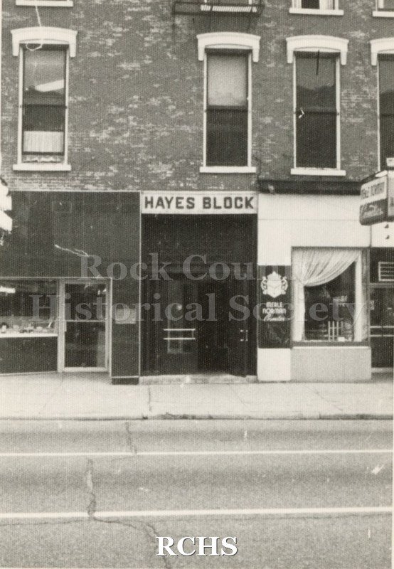 Black and white photograph of the Hayes Block with store fronts: McLean's Jewelry and Merle Norman.